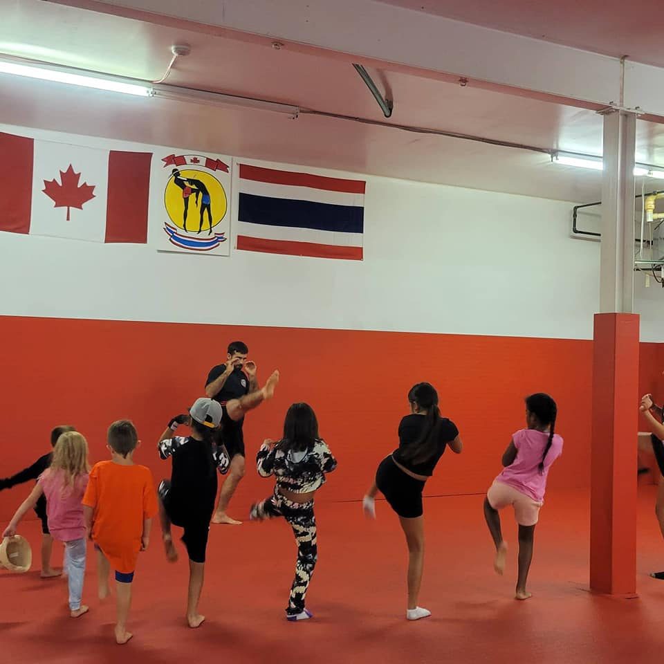 Kids class kicking in front of Canadian and Thai flags